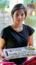 Portrait of woman holding cutting board with text at home