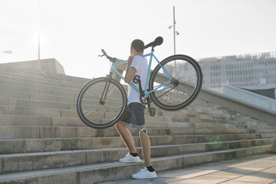 Disabled man carrying bike on stairway