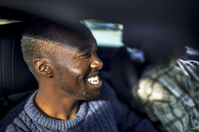 Smiling man with female friend sitting in car during road trip