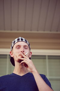 Low angle view of man smoking against building