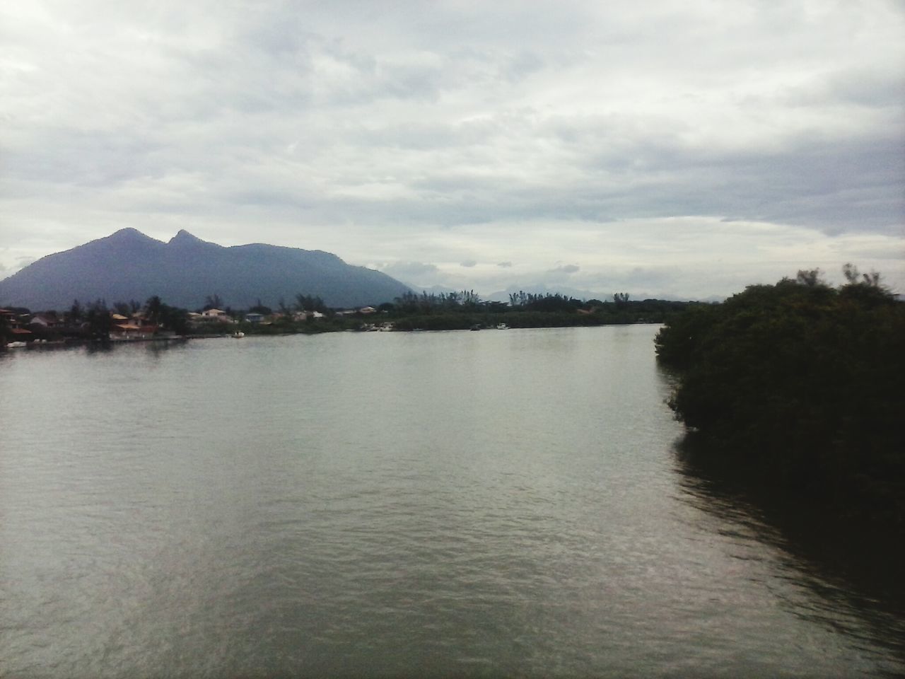 water, mountain, sky, waterfront, cloud - sky, tranquil scene, mountain range, scenics, lake, tranquility, beauty in nature, cloudy, cloud, nature, river, rippled, reflection, built structure, idyllic, outdoors