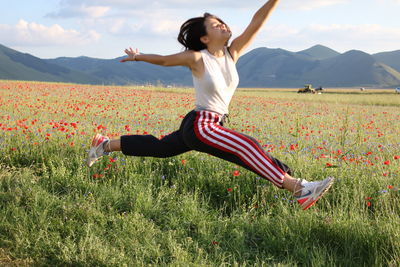 Young woman with arms raised on field