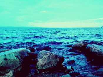 Scenic view of rocks in sea against sky