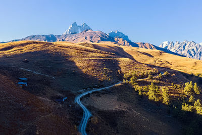 Scenic view of snowcapped mountains against clear blue sky