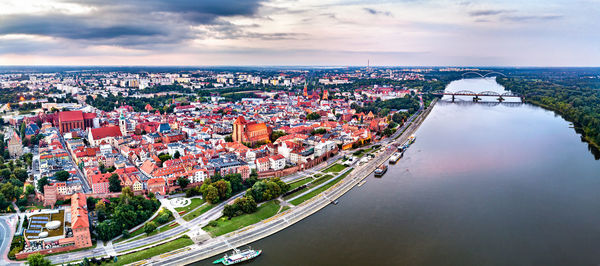 High angle view of illuminated city by river against sky