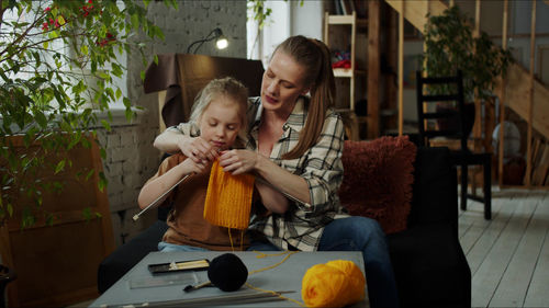 Mother teaching crocheting to daughter