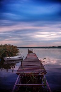 Pier on lake against sky during sunset