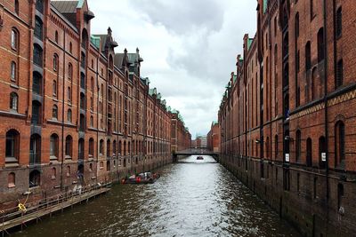 Canal amidst buildings against sky in city