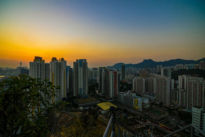 Modern buildings in city against clear sky during sunset