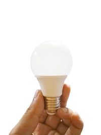 Close-up of hand holding light bulb against white background