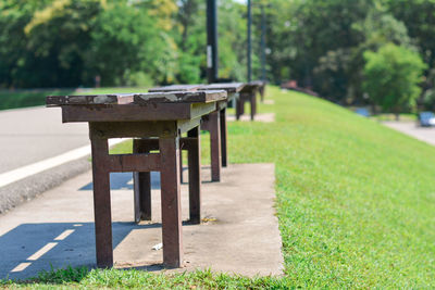 Old metal bench on cement floor and green grass with road in nature park. relaxing time concept.