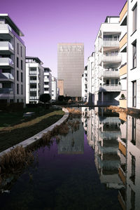 Reflection of buildings in canal against clear sky