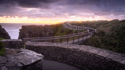 Coastal walkaway leading to horizon with dramatic and cloudy colorful sunset , new zealand