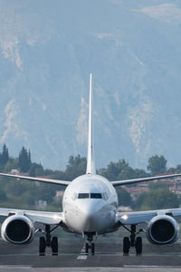 Airplane flying over airport runway against sky