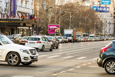 Traffic on road by buildings in city