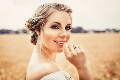 Portrait of smiling bride with blue eyes against sky