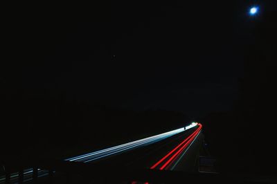 Light trails on road against sky at night