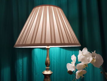Close-up of illuminated electric lamp by white flowers at home