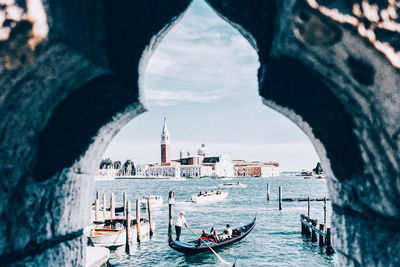 People on boats in river against sky seen through window