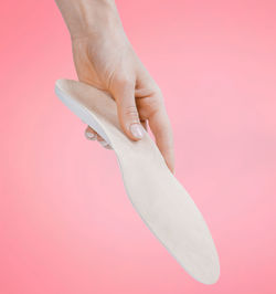 Close-up of human hand holding pink background