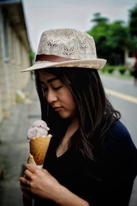 Young woman holding ice cream while standing outdoors