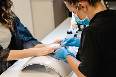 Midsection of woman getting manicure at spa