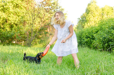 Smiling young woman playing with dog on grass