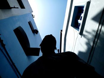 Rear view of silhouette man standing against window