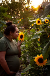 Young woman standing amidst sunflower