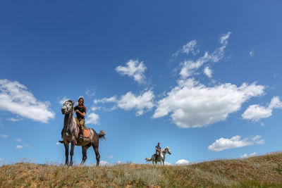 Woman riding horse on field against sky