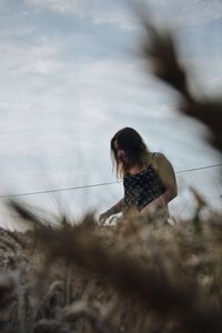 Low angle view of woman on hill against cloudy sky