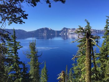 Scenic view of lake and mountains against clear blue sky