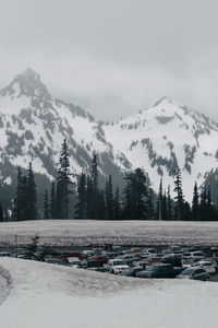 Cars parked at parking lot against snowcapped mountains