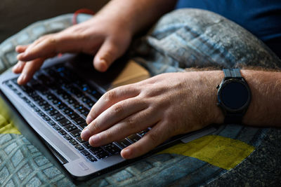 Cropped hands of man using laptop at home