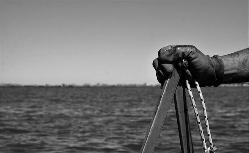 Close-up of hand holding sea against clear sky