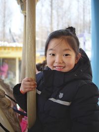 Close-up portrait of cute girl smiling while sitting on carousel