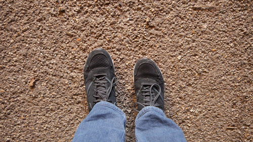 Low section of man standing on sand at beach