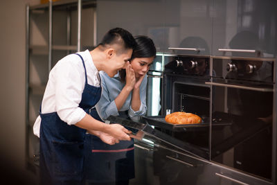 Side view of a woman preparing food in kitchen