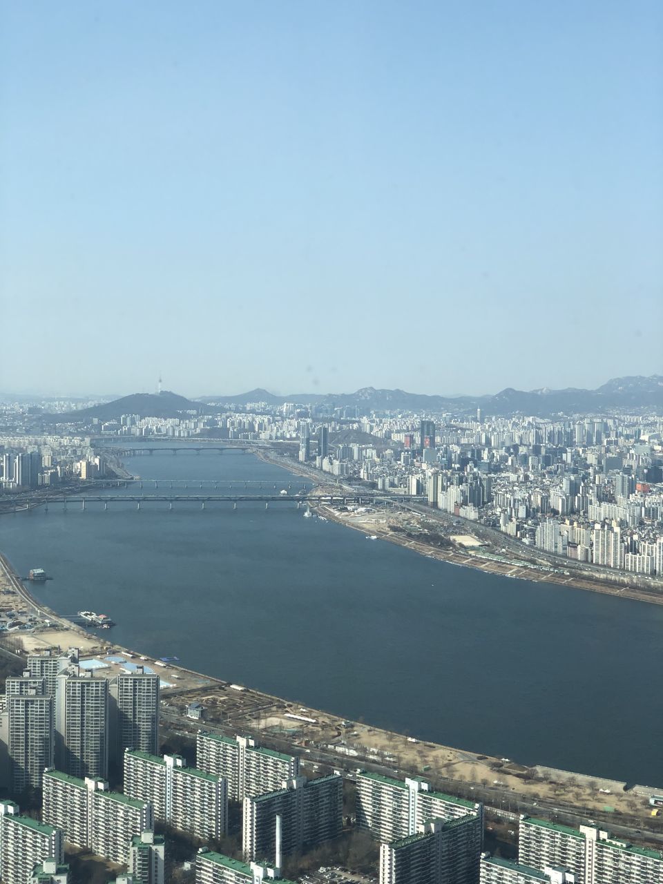 AERIAL VIEW OF CITY BY RIVER AGAINST CLEAR SKY