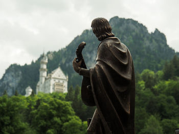 Statue against trees and mountains against sky