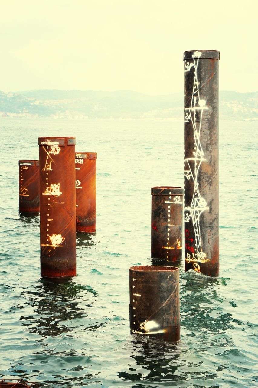 sea, water, horizon over water, metal, waterfront, wooden post, safety, no people, day, sky, protection, metallic, rippled, pole, outdoors, nature, security, close-up, tranquility, copy space