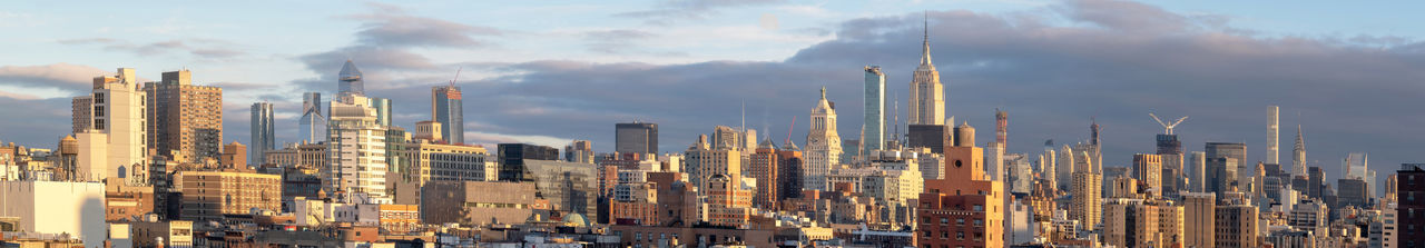 Panoramic view of buildings against cloudy sky