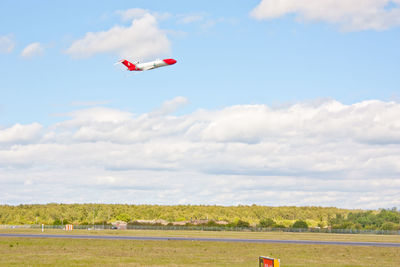 Airplane flying over land against sky