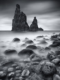 Rock formations in sea against cloudy sky at madeira