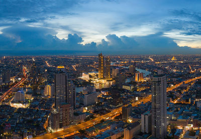 High angle view of illuminated city against cloudy sky