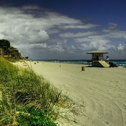 Scenic view of beach against cloudy sky