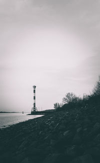 Lighthouse by sea against sky