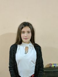 Portrait of young woman standing against wall at home