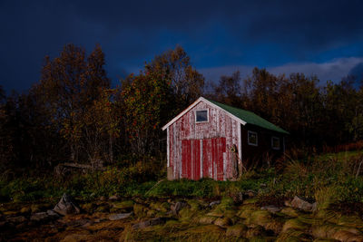 Abandoned house amidst trees on field against sky