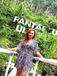 Portrait of smiling woman standing against plants